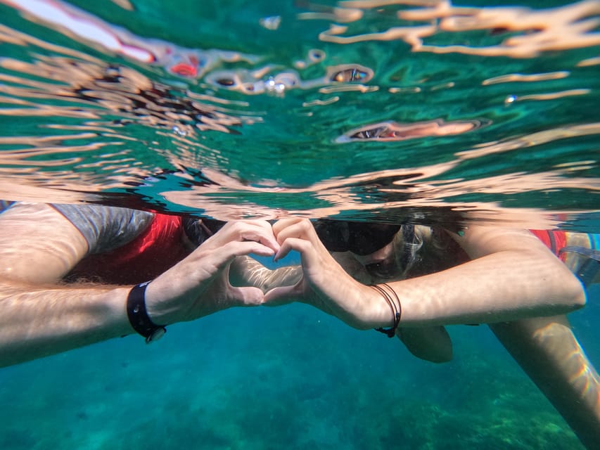 Personne avec masque et tuba flottant au-dessus de rochers clairs dans une eau turquoise