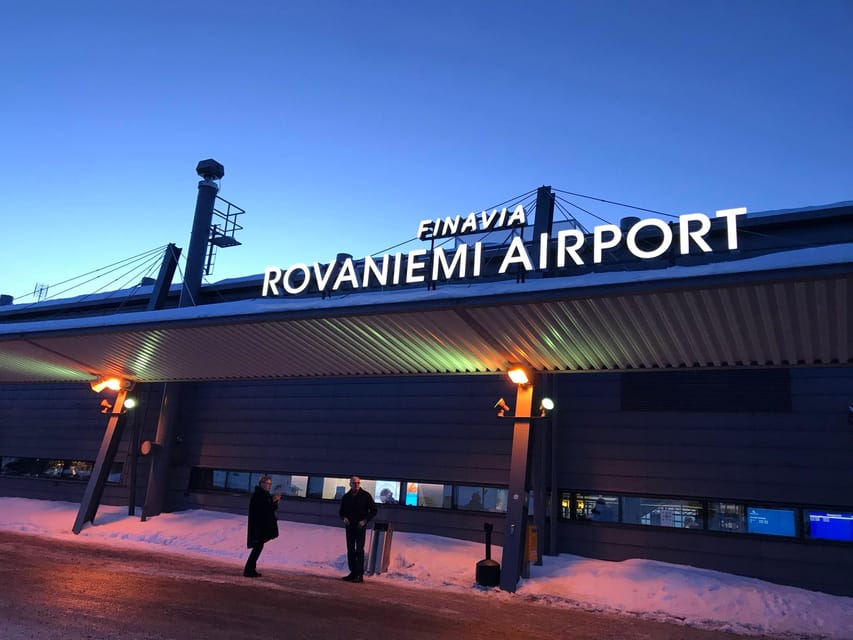 A passenger van waiting outside a snow-covered airport terminal