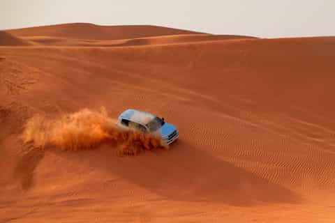 Dune buggies parked on a ridge at sunset in the Dubai desert