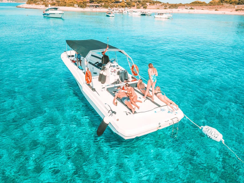 Speedboat with guests sunbathing at anchor in the turquoise water of a bay