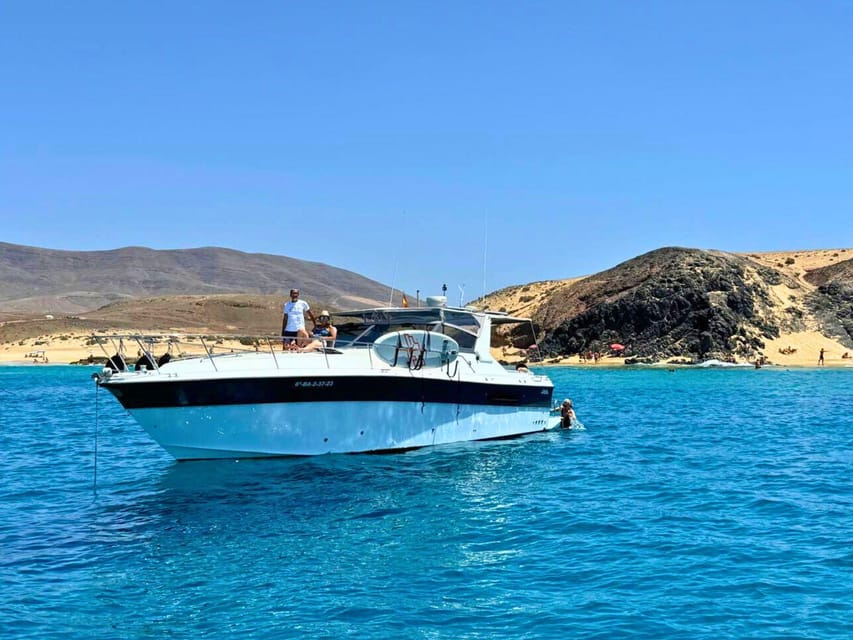 A white motor yacht anchored in turquoise water beneath Papagayo's ochre cliffs