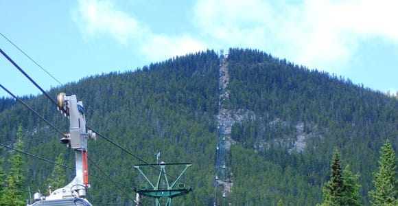 A Sulphur Mountain gondola cabin on its cable with forested mountain slopes behind