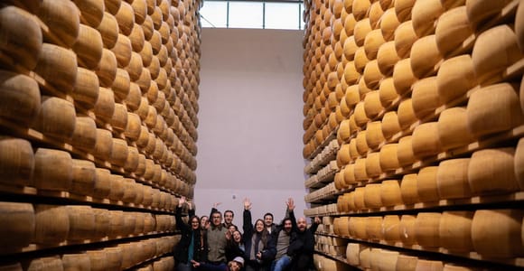 Large wheels of Parmigiano Reggiano ageing on tall wooden shelves in a dairy store room
