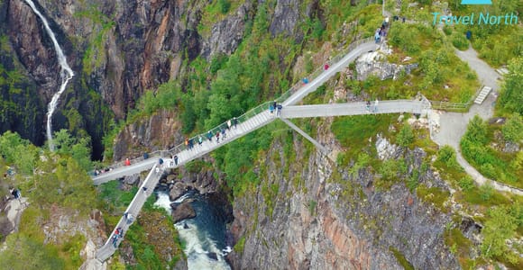 A broad waterfall plunging into a rocky valley surrounded by green Hardanger mountains