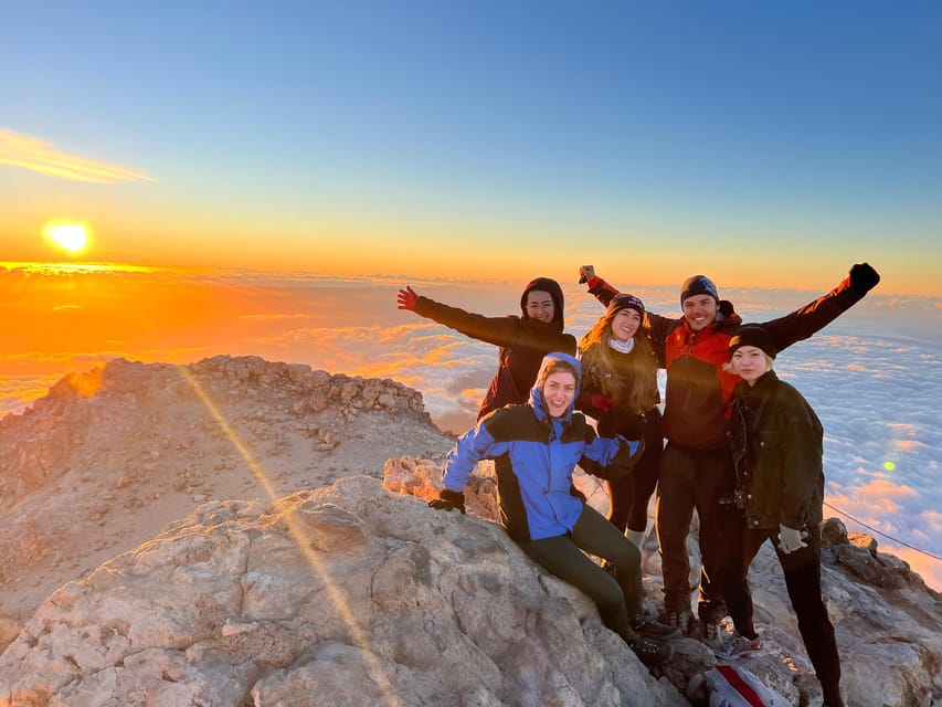 Walkers on rocky ground above the clouds at sunrise