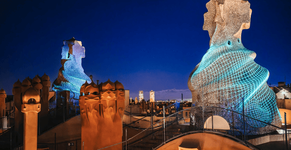 Sculptural chimneys on La Pedrera’s rooftop illuminated against the night sky
