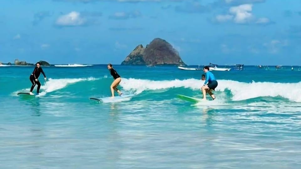 A beginner surfer carrying a board across a broad sandy beach