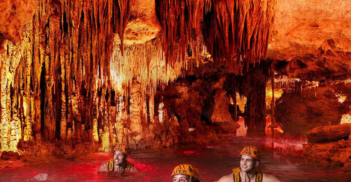 Three visitors in orange Xplor helmets swimming the underground river at night