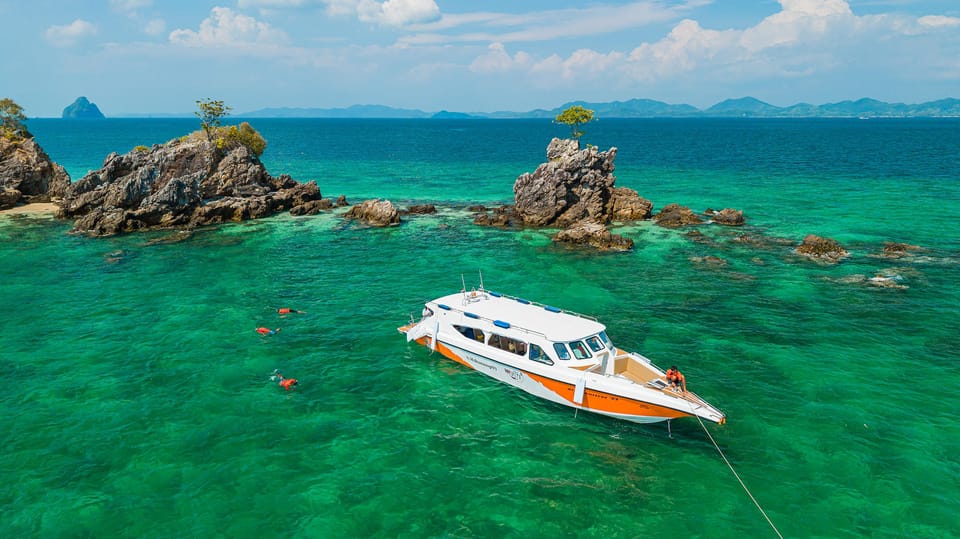 Shallow turquoise water and white sand on a small island east of Phuket, with a speedboat offshore