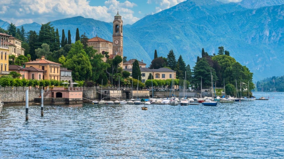 A passenger ferry approaching a colourful Lake Como village beneath green mountains