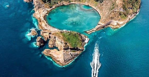 Aerial view of the ring-shaped volcanic islet of Vila Franca do Campo with its turquoise lagoon and a boat wake