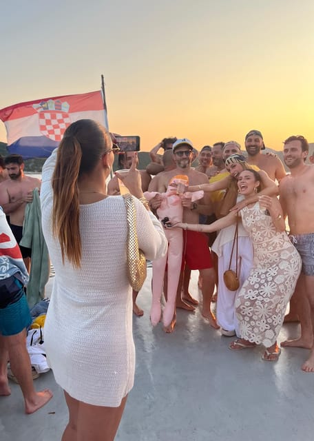 Party boat cruising past Dubrovnik’s rocky coast in warm evening light