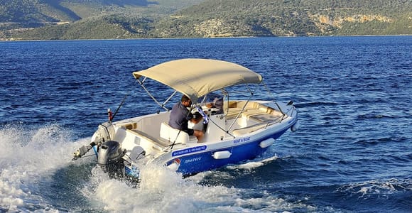 A small motorboat with a beige sun canopy speeding through dark blue water, with green hills behind