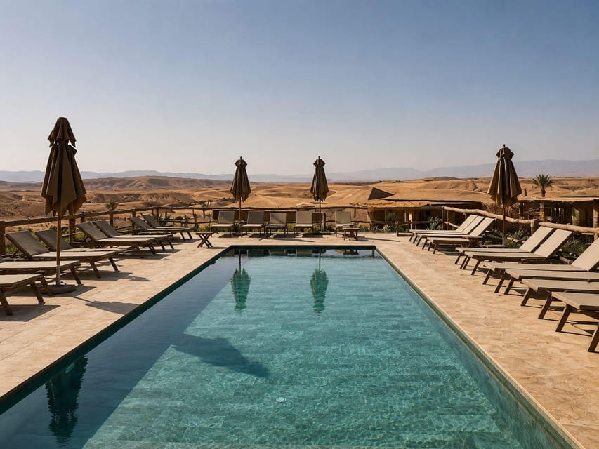 Piscine entourée de transats et de parasols devant un paysage aride