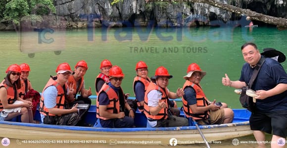 Forested limestone entrance beside calm water at Puerto Princesa Underground River