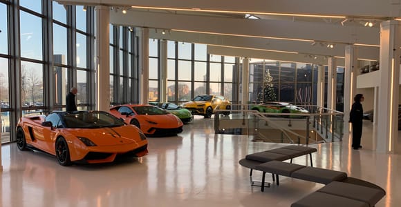 Red Italian sports cars displayed beneath bright lights in a modern motor museum