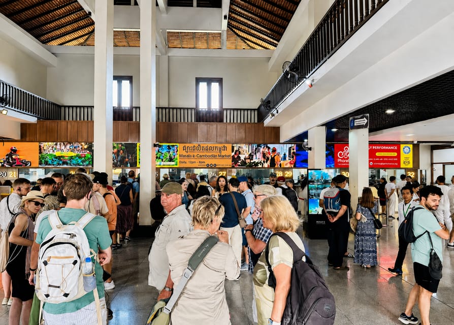 Sandstone gallery at Angkor with a row of square pillars and a visitor's ticket check point in the shade at the entrance