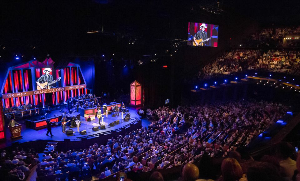 A crowd watching a band performing on a stage inside the Grand Ole Opry.