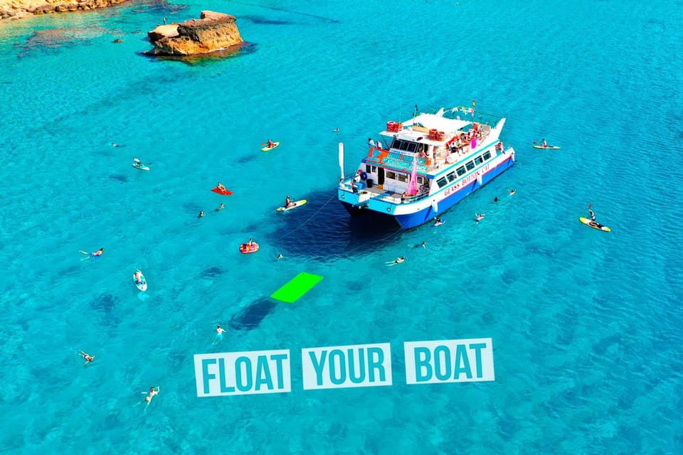 A sightseeing boat anchored off a rocky Ibiza beach while guests swim nearby