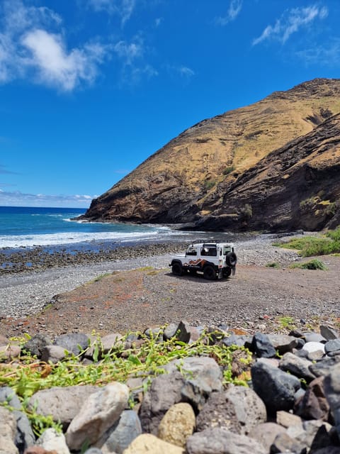 A four-wheel-drive vehicle following a sandy track across Porto Santo's pale dunes below dry volcanic hills