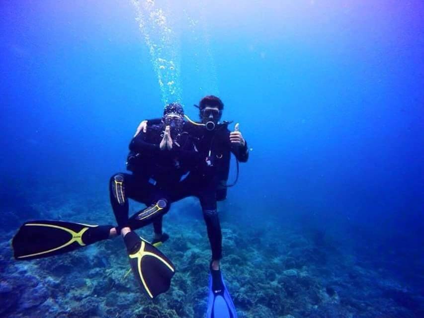 A diver in full equipment swimming beside reef fish in the waters off Nha Trang