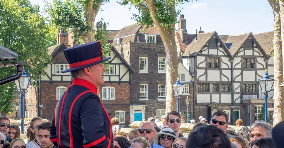 A Yeoman Warder in blue undress uniform leading a tour group inside the Tower of London