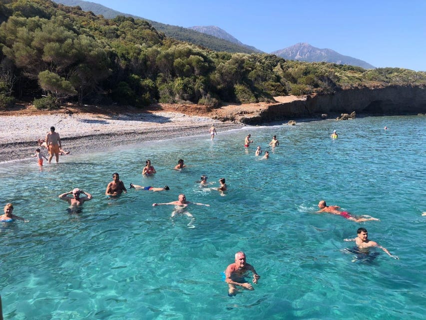 A white excursion boat anchored in a clear Aegean cove