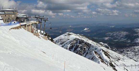 Cable-car summit station on a snowy ridge above a wide valley