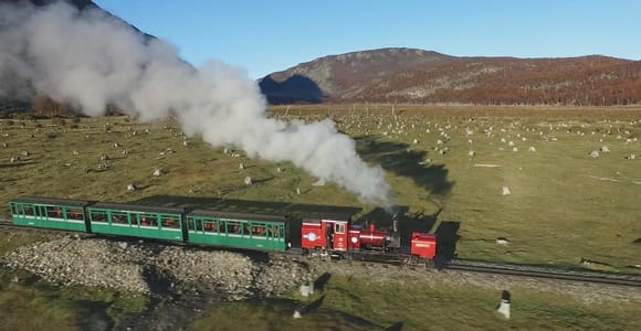 Kleine Dampfbahn in einem bewaldeten Tal unter den Bergen Feuerlands