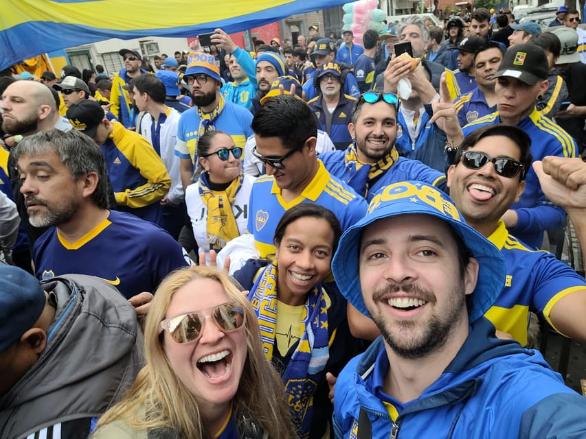 Football supporters raising blue and yellow flags inside a crowded Buenos Aires stadium