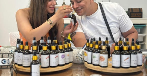Two adults smelling a fragrance sample between rows of labelled dropper bottles at a perfume workshop