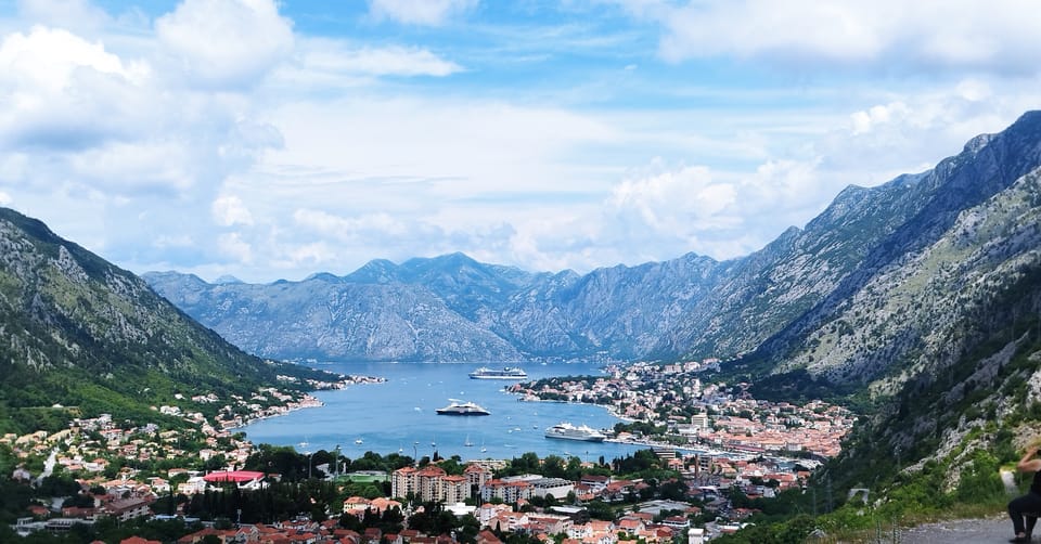 Cruise ship beyond Kotor harbour with the walled old town at the foot of the mountains