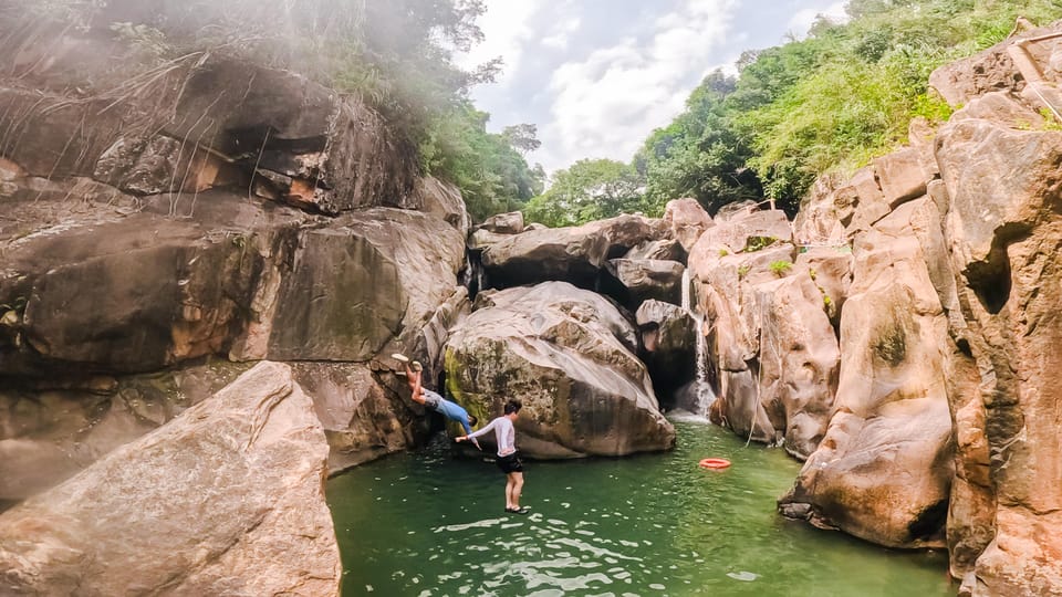 Large boulders and a forest pool along the trail at Ba Ho Waterfalls