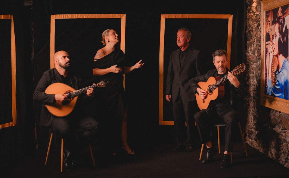 A singer performing beside a Portuguese guitar in warm stage light