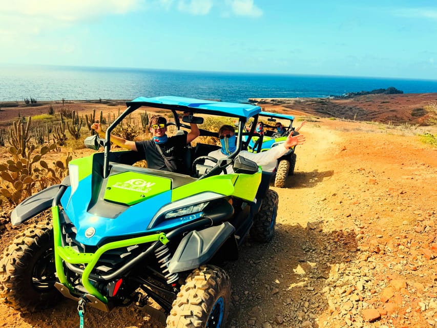 Two UTVs with waving drivers on a red dust track among cacti