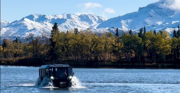A broad tundra valley and snow-covered Alaska Range peaks in Denali